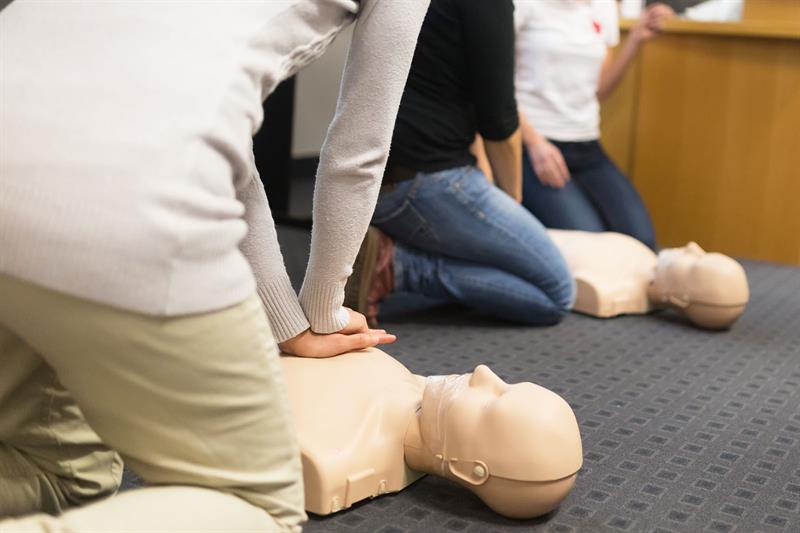 group of adult education students practicing chest compression on dummies