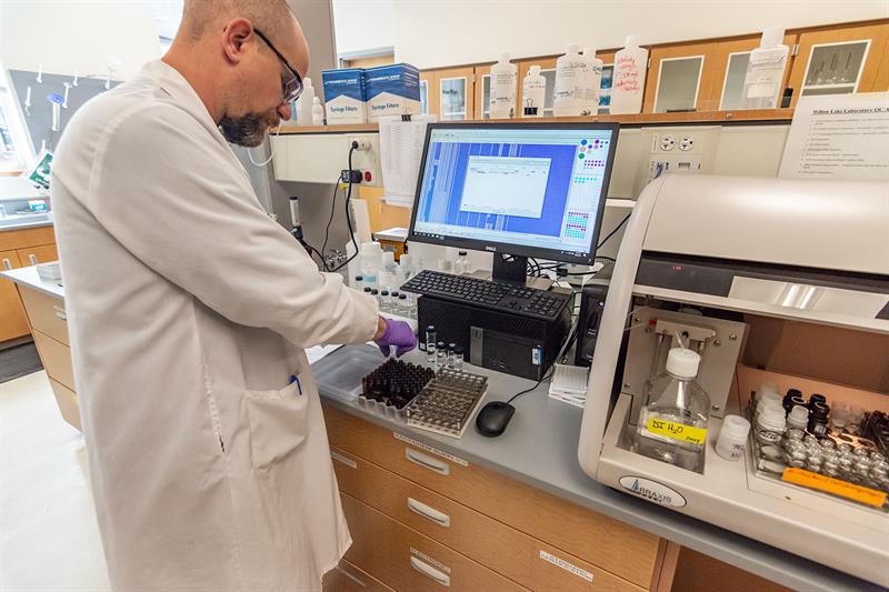 lab technician at willow lake prepares water samples next to caas equipment 