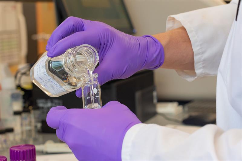 lab technician gloved hand pours water sample into vialweb_1600x1067_color