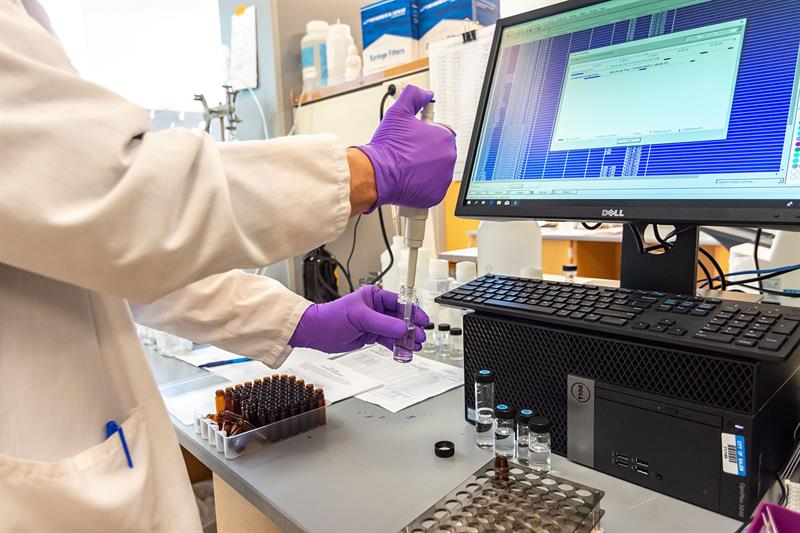 lab technician hand preparing water samples for elisa testing and computer