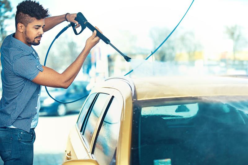 man washing car with pressure nozzle