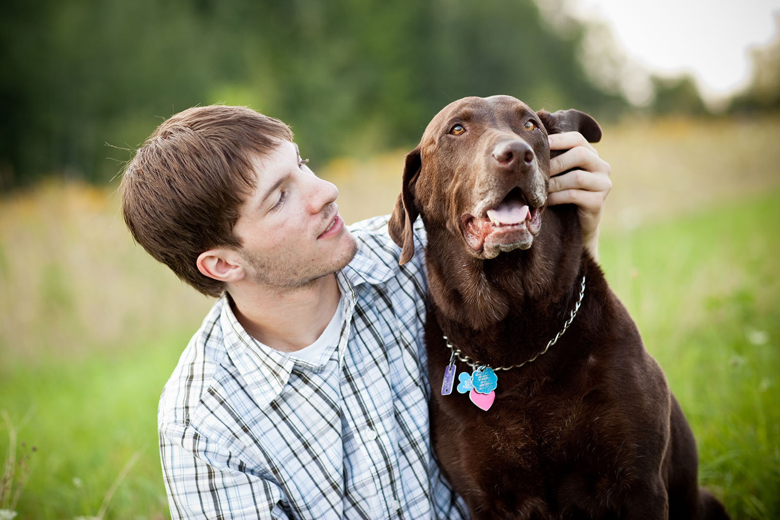 Young boy petting dog in a field