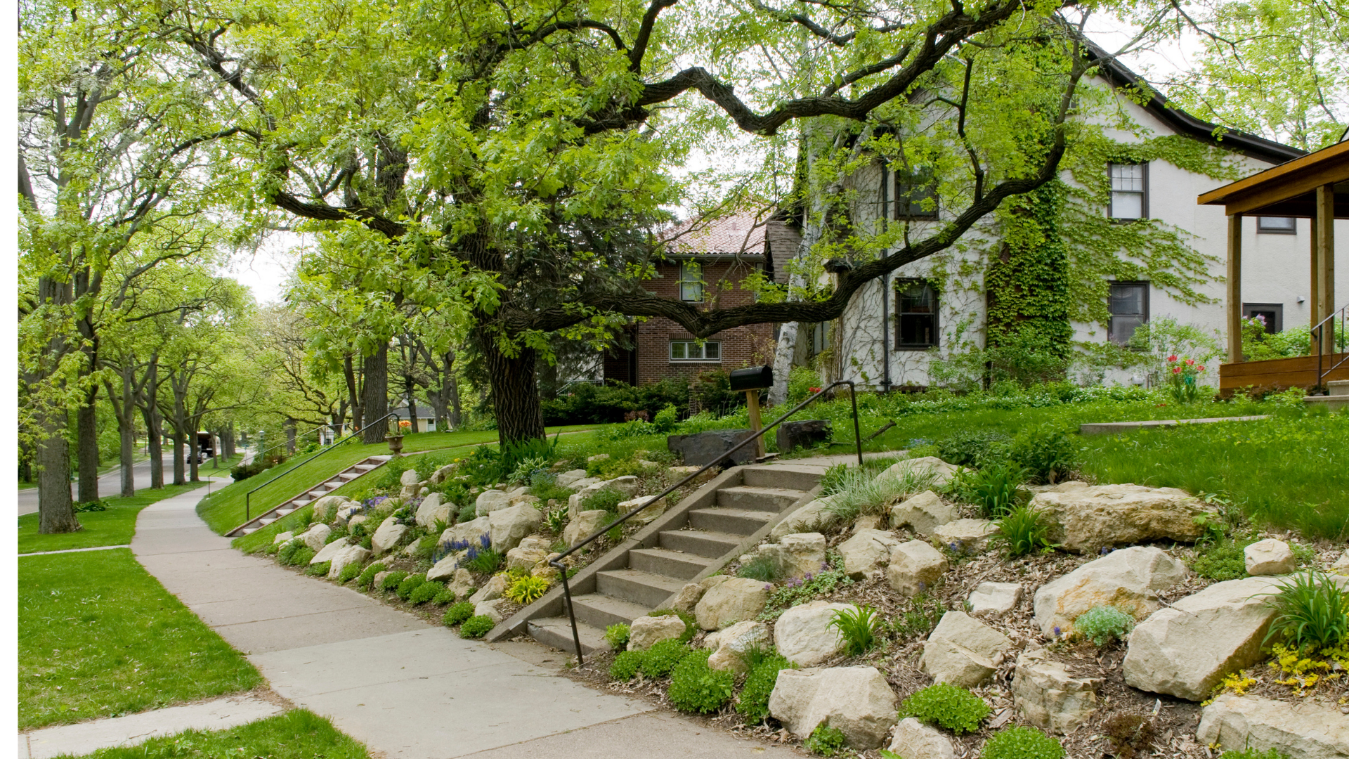 Neighborhood house on path with trees rocks.