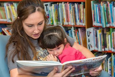 woman reading to little girl wearing pink