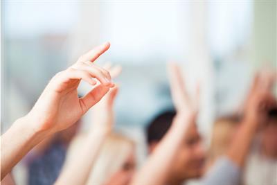 group of students raising their hands in class