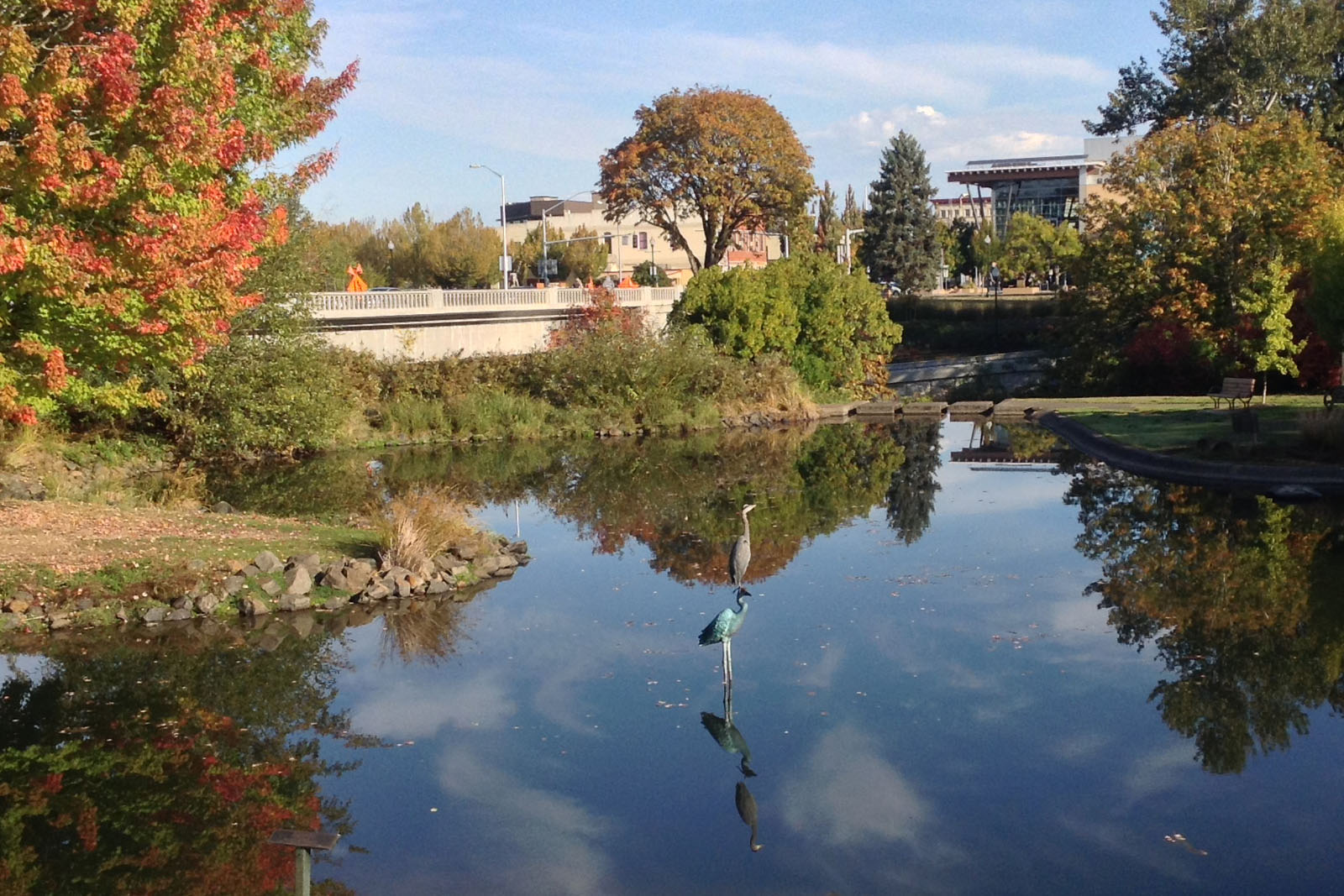 heron standing on heron statue in mirror pond