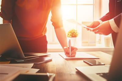 man and woman working together in office setting with sunlight coming in