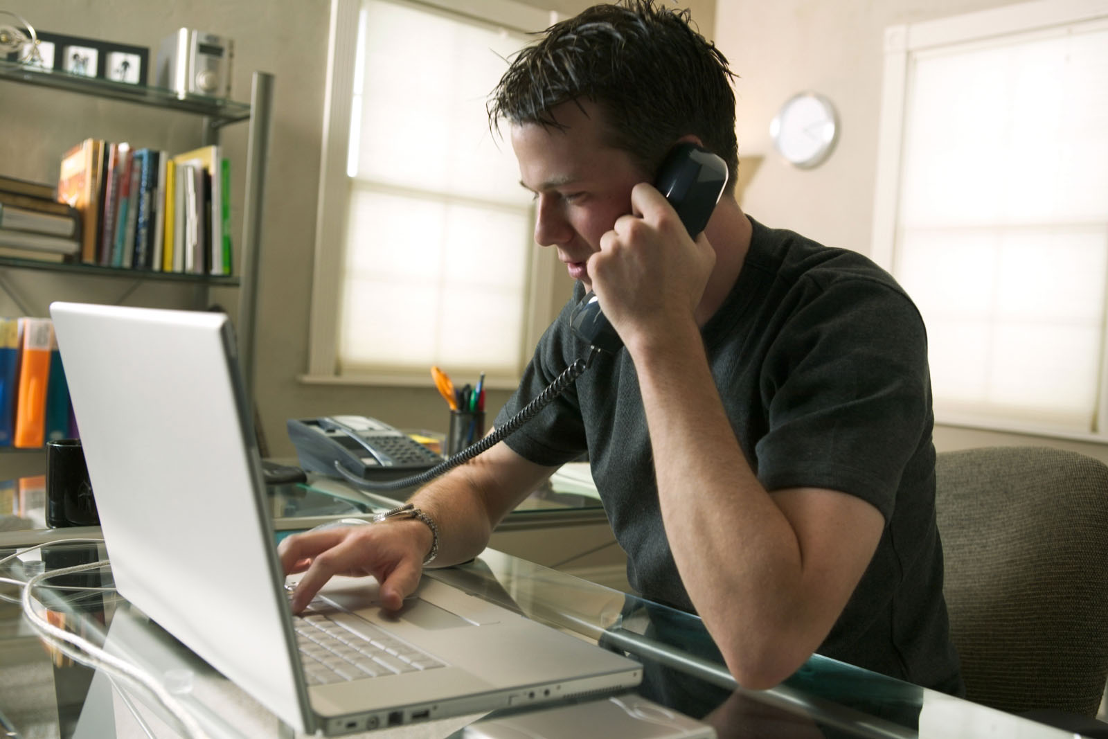 man speaking on phone and typing on computer