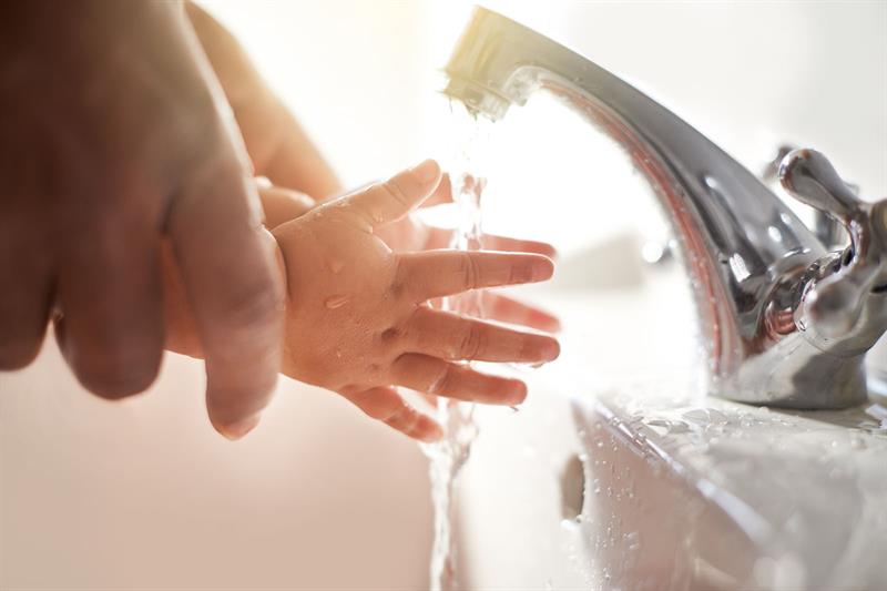 father helping baby wash hands