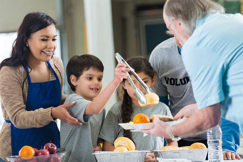 young hispanic family volunteering to serve food in soup kitchen