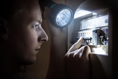 young man attempting to restore power looking at breaker panel