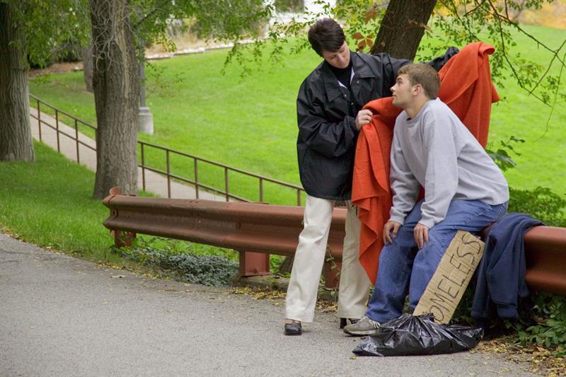 volunteer giving homeless man blanket